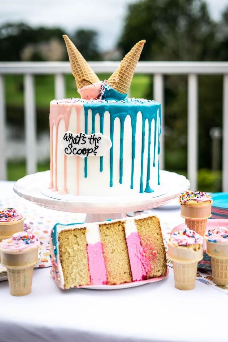 there is a cake with ice cream and sprinkles on the table next to cupcakes