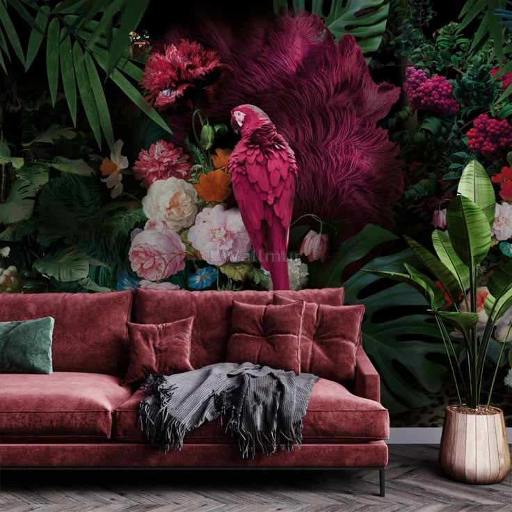 a red couch sitting in front of a wall with flowers and birds on top of it