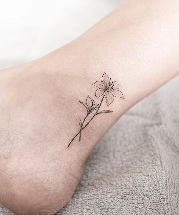 a small flower tattoo on the ankle that is sitting on someone's foot,