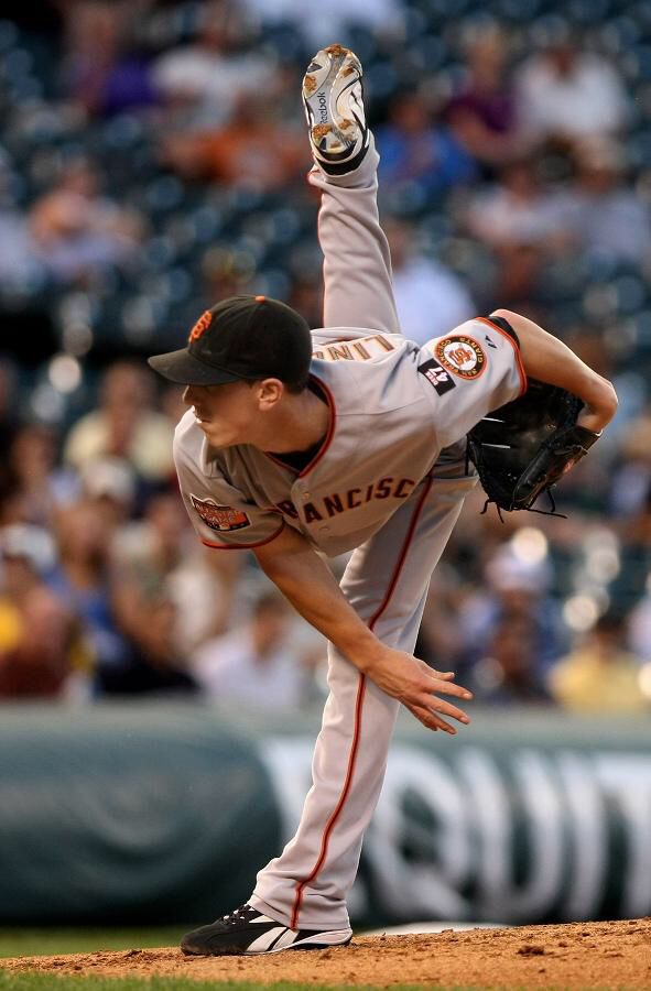 a baseball player pitching a ball on top of a field in front of a crowd