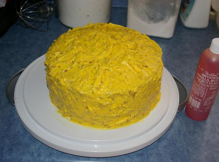 a yellow frosted cake sitting on top of a white plate