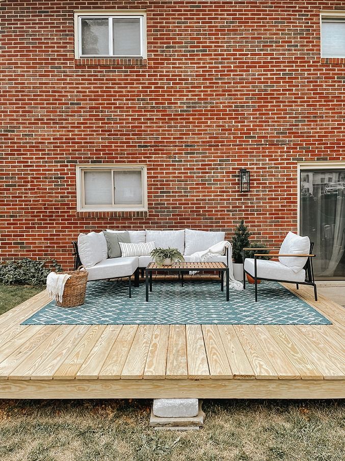 a wooden deck with two couches and a table on it in front of a brick building