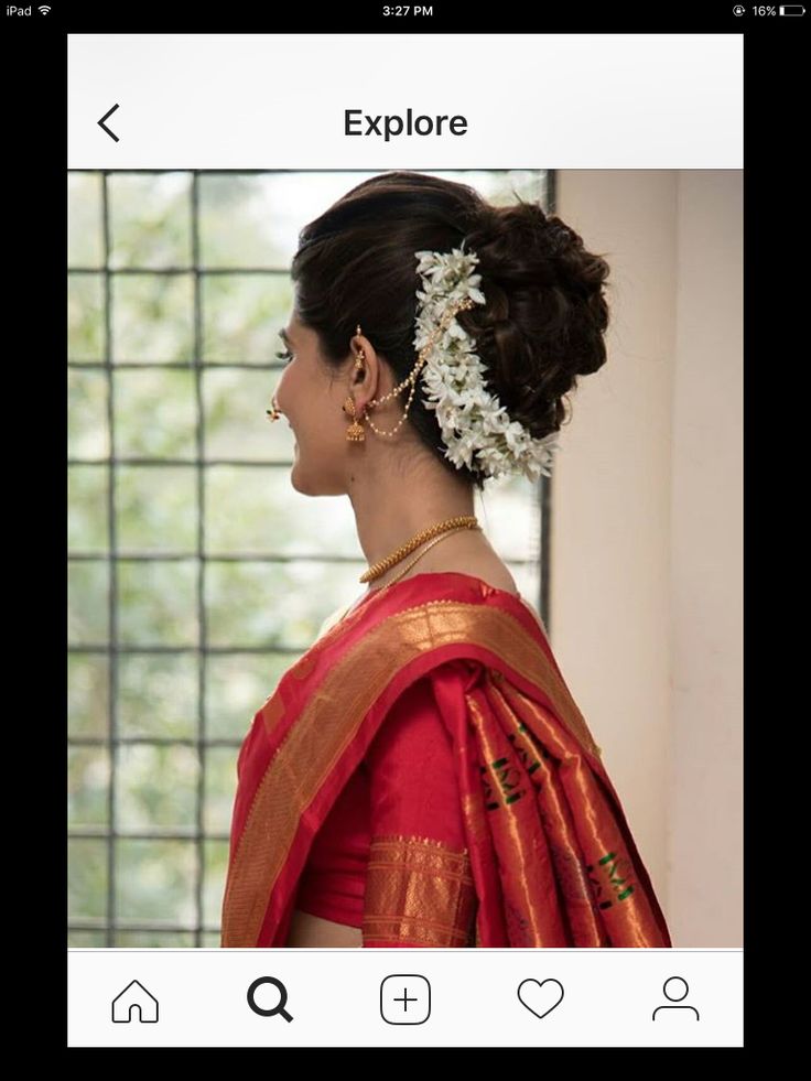 a woman wearing a red and gold sari with flowers in her hair looking out the window