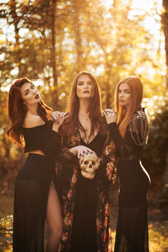 three beautiful women dressed in black posing for a photo with a skull on their chest