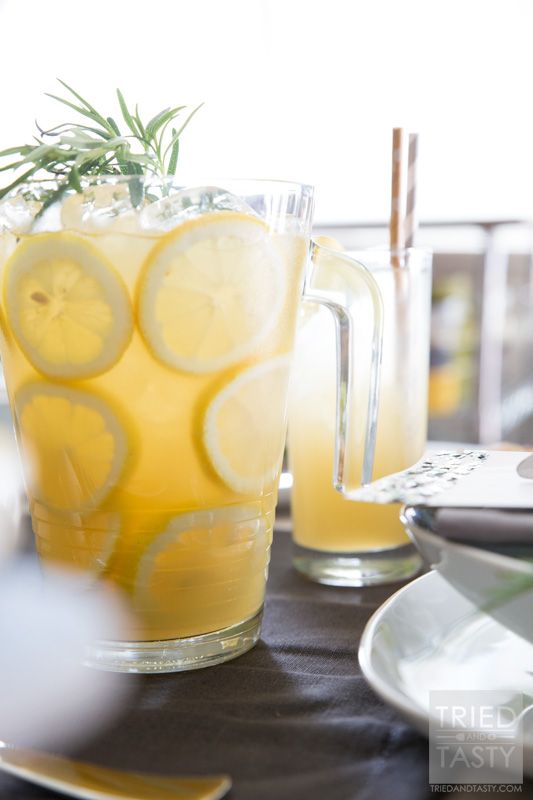 there is a pitcher of lemonade and two glasses with lemon slices on the table