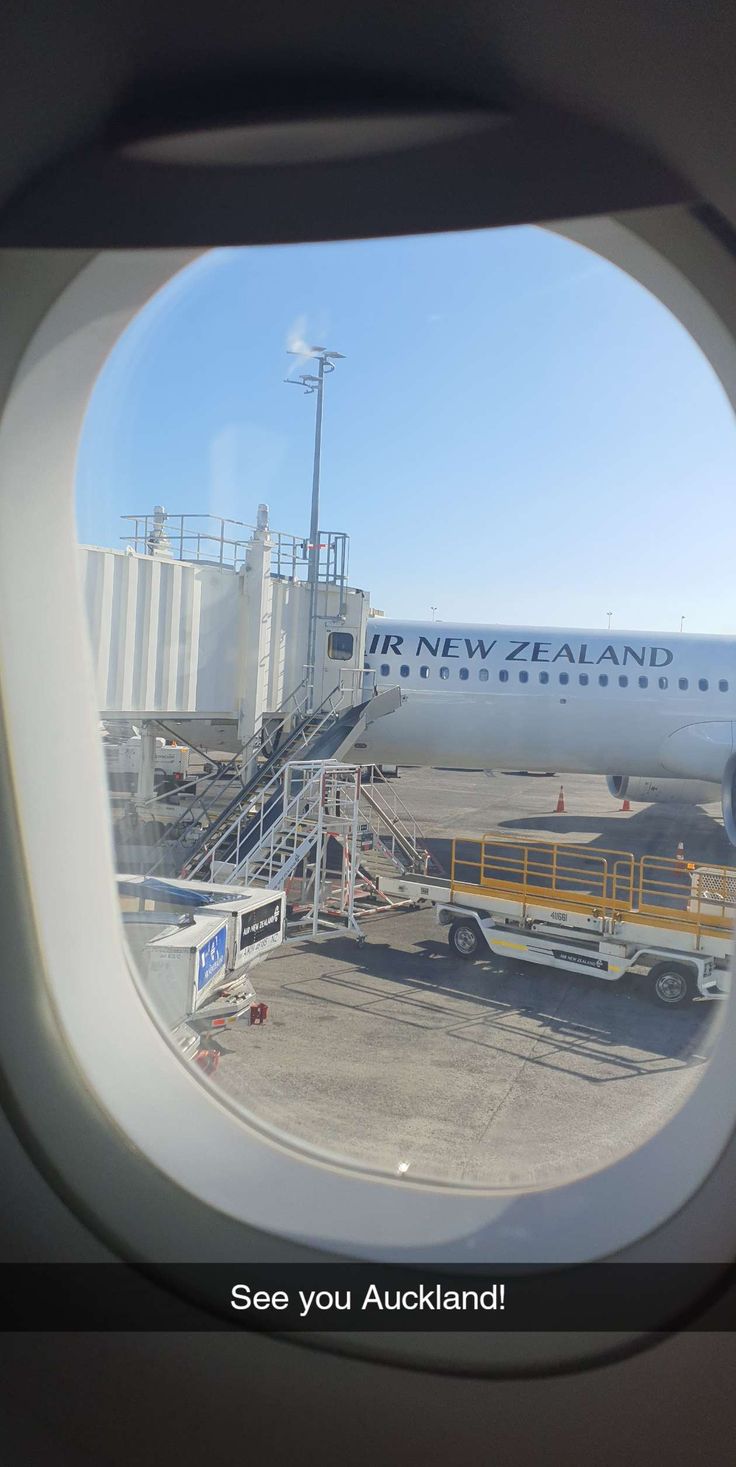 an air new zealand jetliner sitting on top of an airport tarmac with stairs leading up to it