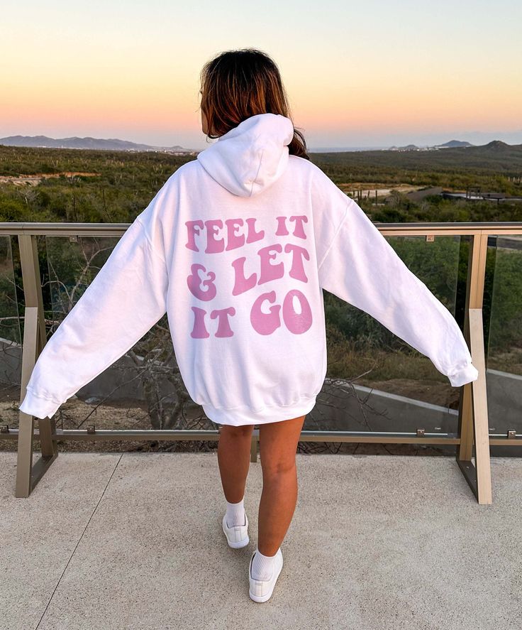 Introducing our groovy and empowering "Feel It And Let It Go" Mental Health Hoodie! Designed to embrace the journey of emotions and encourage mindfulness, this hoodie combines a cute and preppy style with a retro-inspired, groovy font that proudly displays the words on the back. Crafted with care, this mental health sweatshirt is made from high-quality materials, ensuring both comfort and durability. Its cozy fabric keeps you warm and snug, while its trendy hoodie style offers a comfortable and Athleisure Hoodie With Graphic Print For Leisure, Athleisure Graphic Print Hoodie For Leisure, Trendy White Sweats For Leisure, Athleisure Hoodie With Letter Print For Leisure, Relaxed Fit Hoodie With Letter Print For Leisure, Relaxed Fit Letter Print Hoodie For Leisure, Relaxed Fit Hoodie For Leisure, Spring Hoodie With Letter Print For Leisure, White Oversized Hoodie With Screen Print