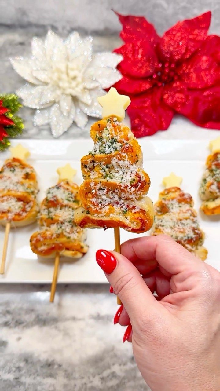 a person is holding some food on a stick with christmas decorations in the back ground