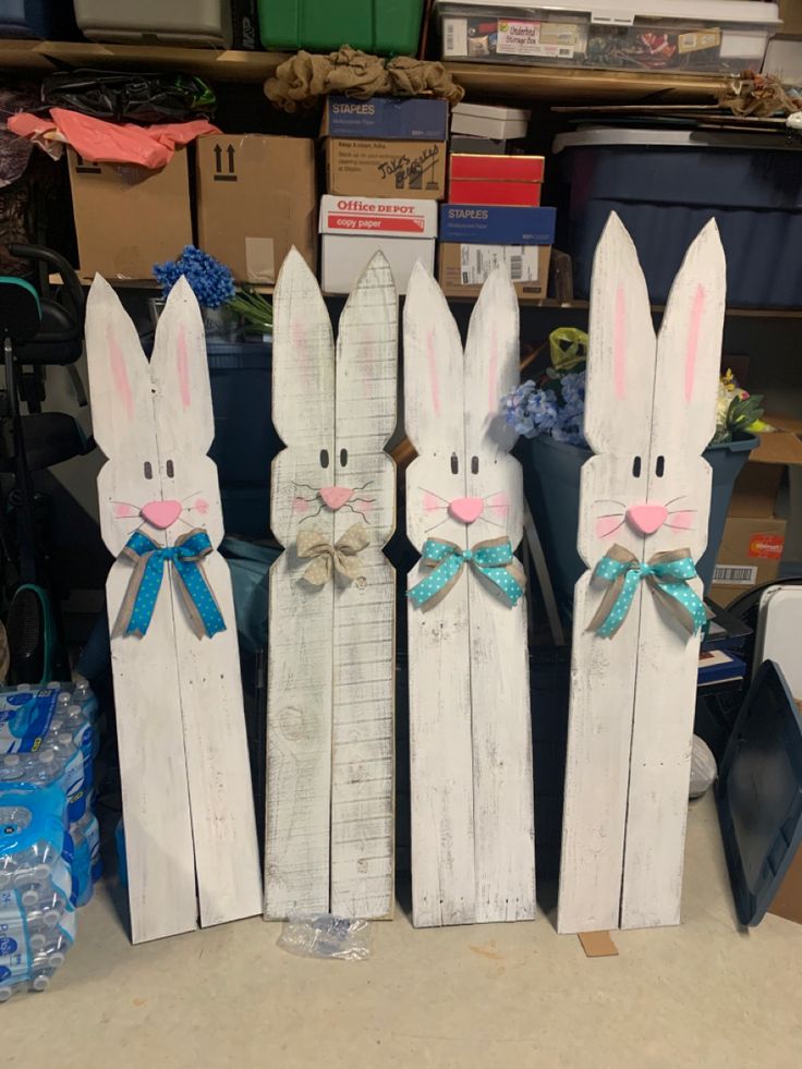 three wooden rabbits with bows on their ears are standing next to each other in front of boxes