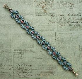 a blue bracelet with flowers on it sitting on top of a piece of paper