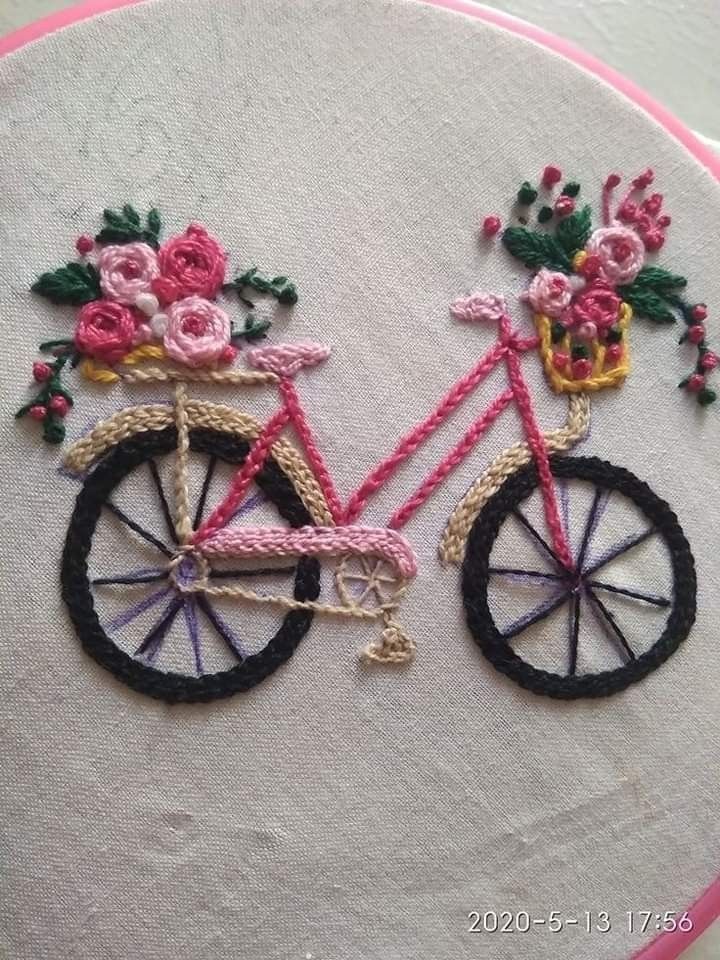 a pink bicycle with flowers on the front is embroidered onto a white fabric wall hanging