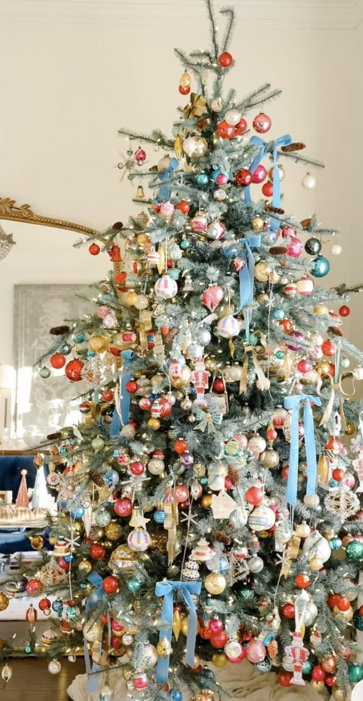 a decorated christmas tree in a living room with blue ribbon and ornaments on the top