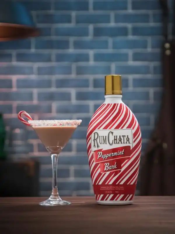 a bottle of rumchata next to a martini glass filled with candy canes