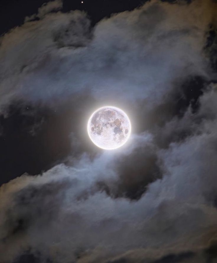 the moon is shining brightly in the cloudy sky