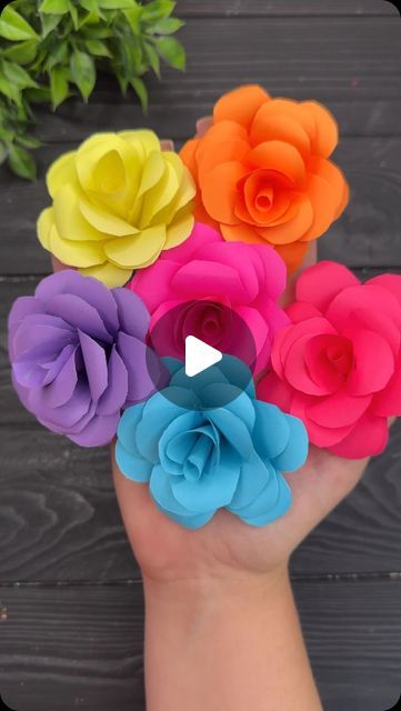 colorful paper flowers in the palm of someone's hand