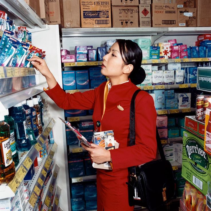 a woman in a red uniform is looking at canned food items on the refrigerator door