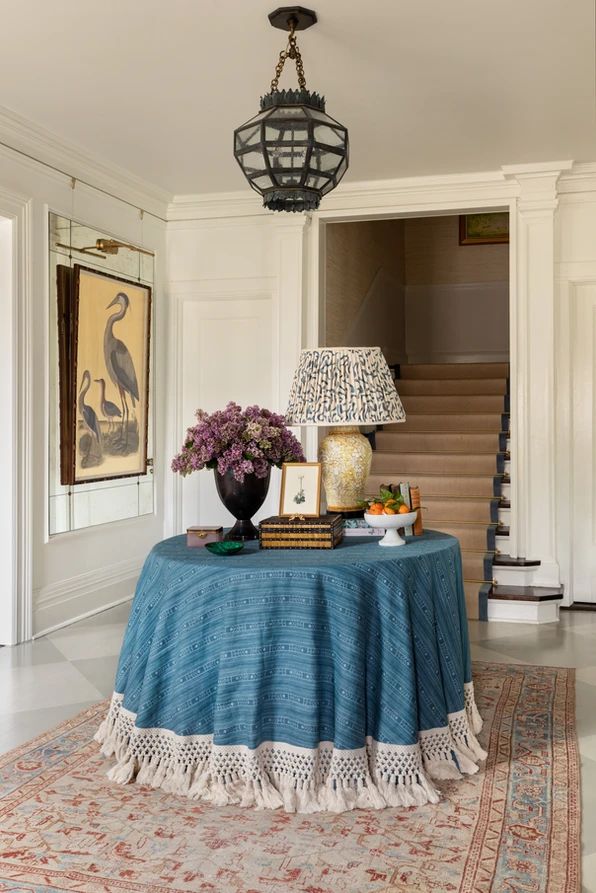 a table with a blue cloth on it in front of a stair case and chandelier