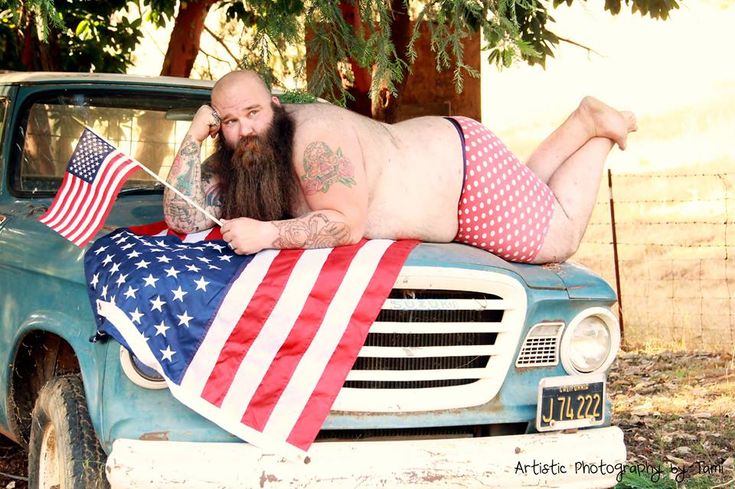 a man laying on the hood of a truck with an american flag