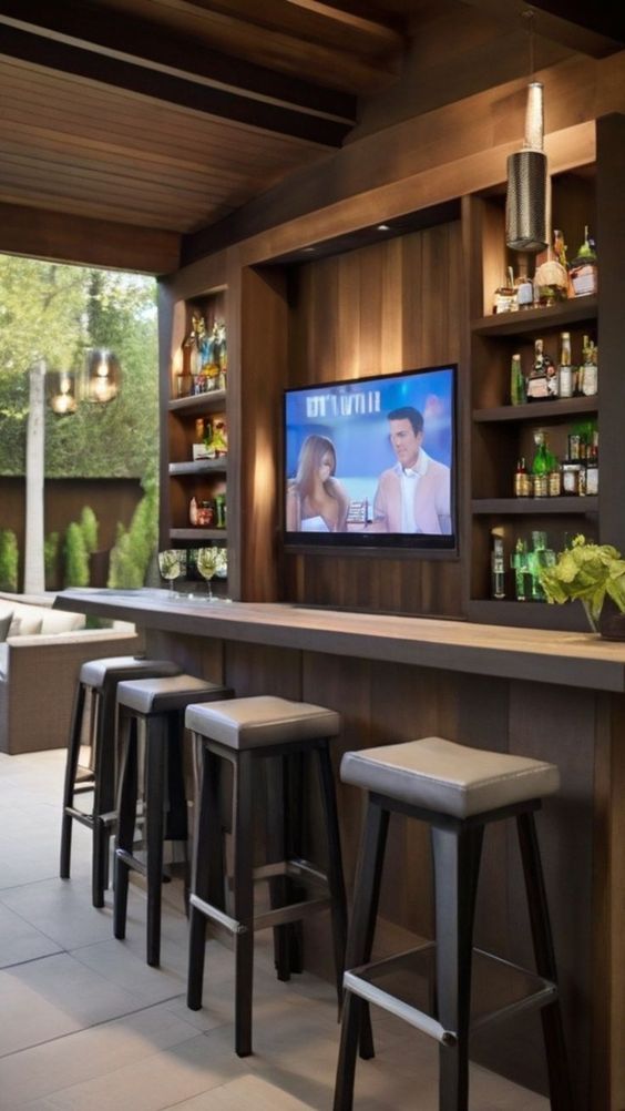 a bar with stools and a television mounted on the wall above it in a home