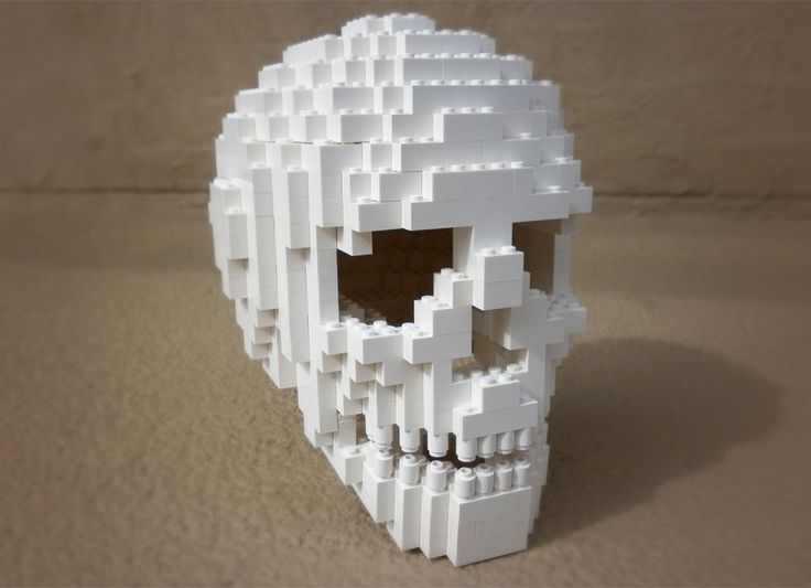 a white skull made out of legos sitting on top of a table next to a wall