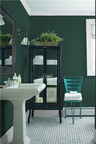 a bathroom with green walls and white tile flooring, including a pedestal sink in the center