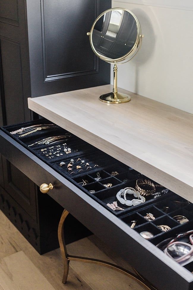 an open drawer with jewelry in it and a mirror on the top shelf above it