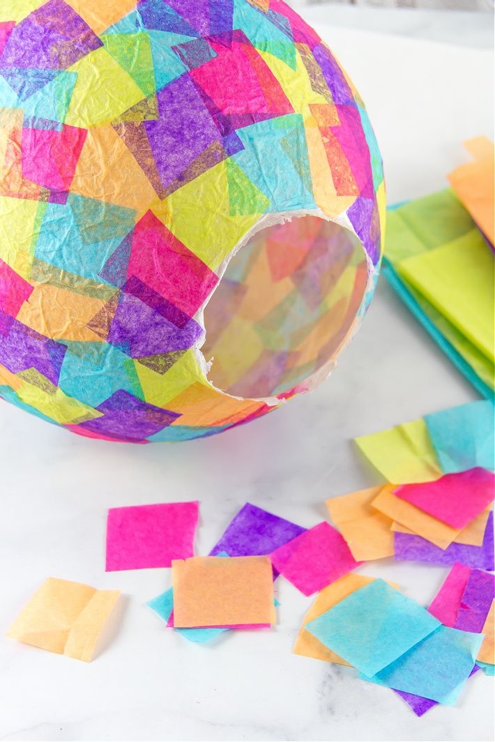 an easter egg made out of paper and colored sticky notes on a table with scissors