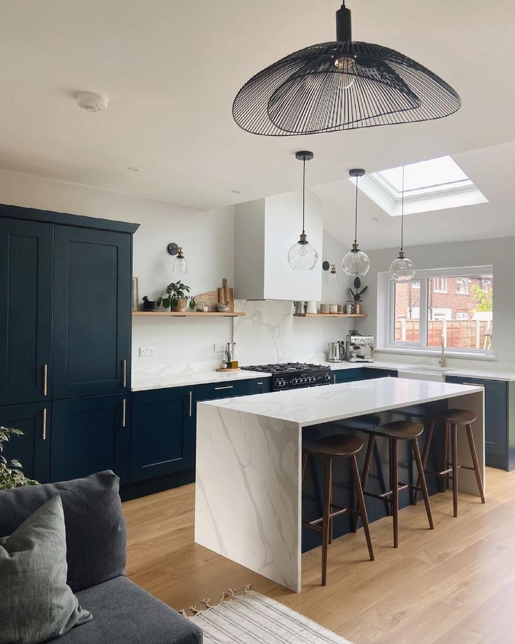 a kitchen with blue cabinets and white counter tops, an island in the middle has stools on it