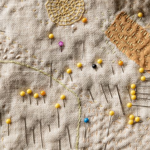 an embroidered piece with pins and needles on it