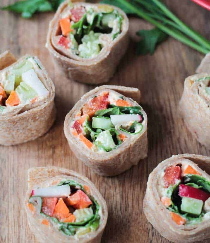 there are several rolls with vegetables in them on the wooden table next to carrots and celery