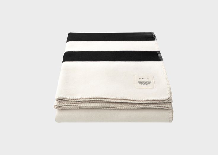 two black and white blankets folded on top of each other, one with a stripe