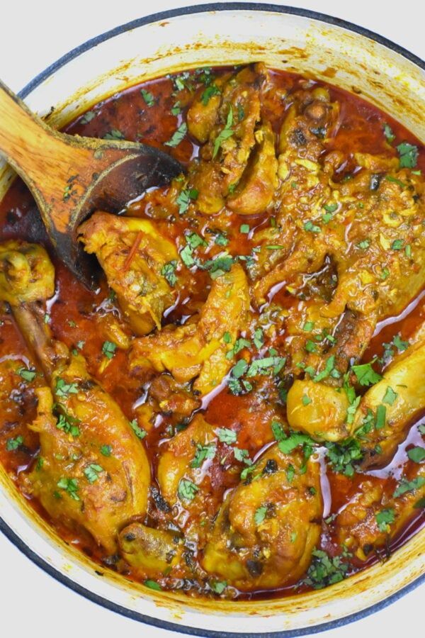 chicken curry in a pot with a wooden spoon