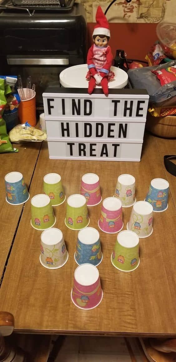 a table topped with cups and a sign that says find the hidden treat on it