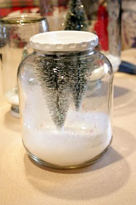 a glass jar filled with snow and christmas trees in the middle of a kitchen counter