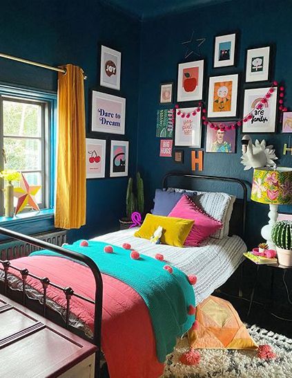 a bedroom decorated in bright colors with pictures on the wall above the bed and below the bed is a black metal bed frame