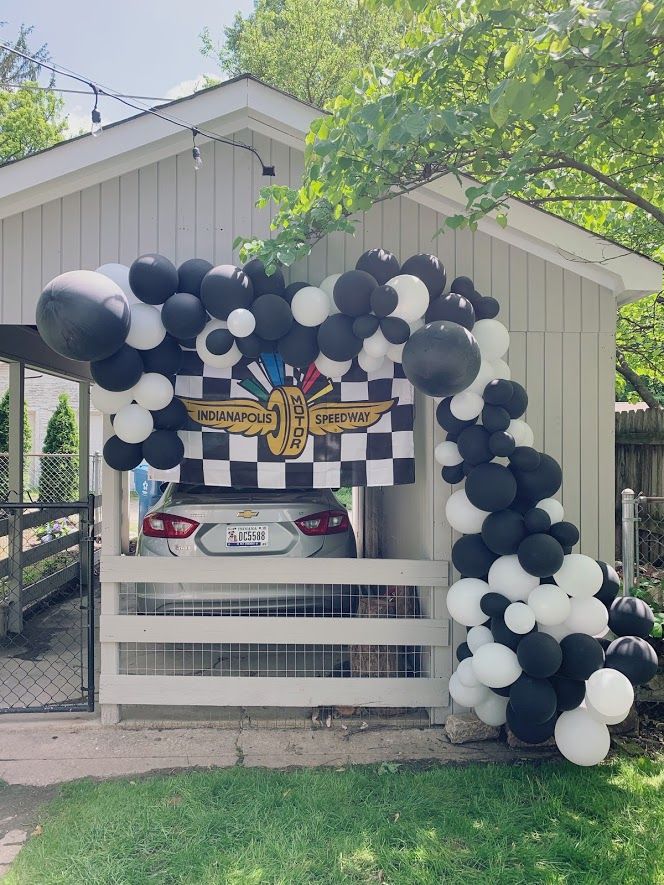 black and white balloons are tied to the back of a car in front of a house