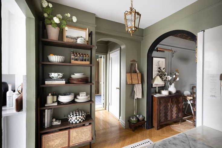 a room with green walls and wooden shelves filled with dishes on top of each shelf