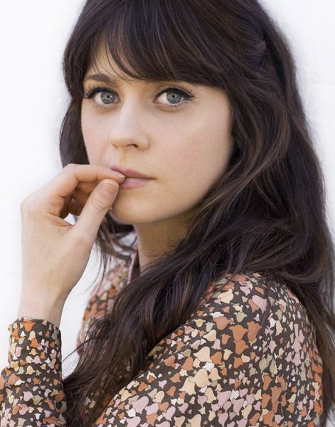 a close up of a person with long hair and blue eyes wearing a floral shirt