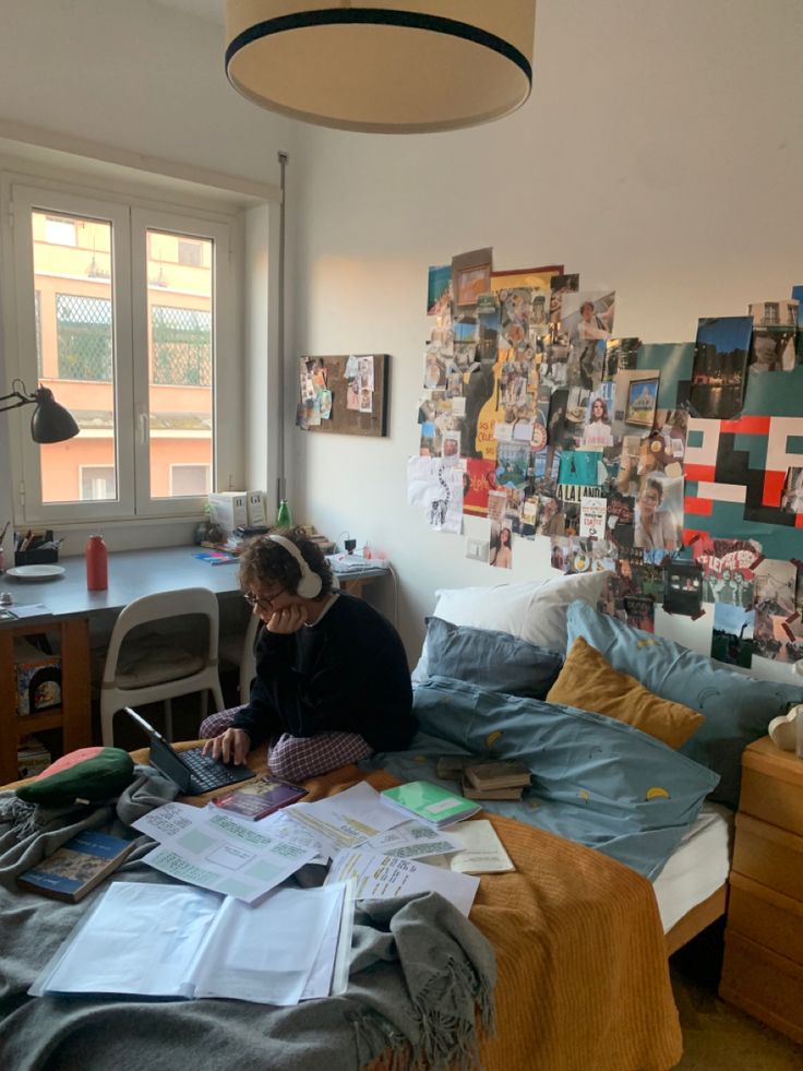 a woman sitting on top of a bed next to a desk with a laptop computer