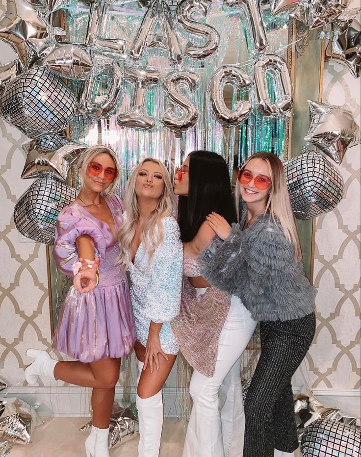 three beautiful women standing next to each other in front of balloons and disco ball decorations