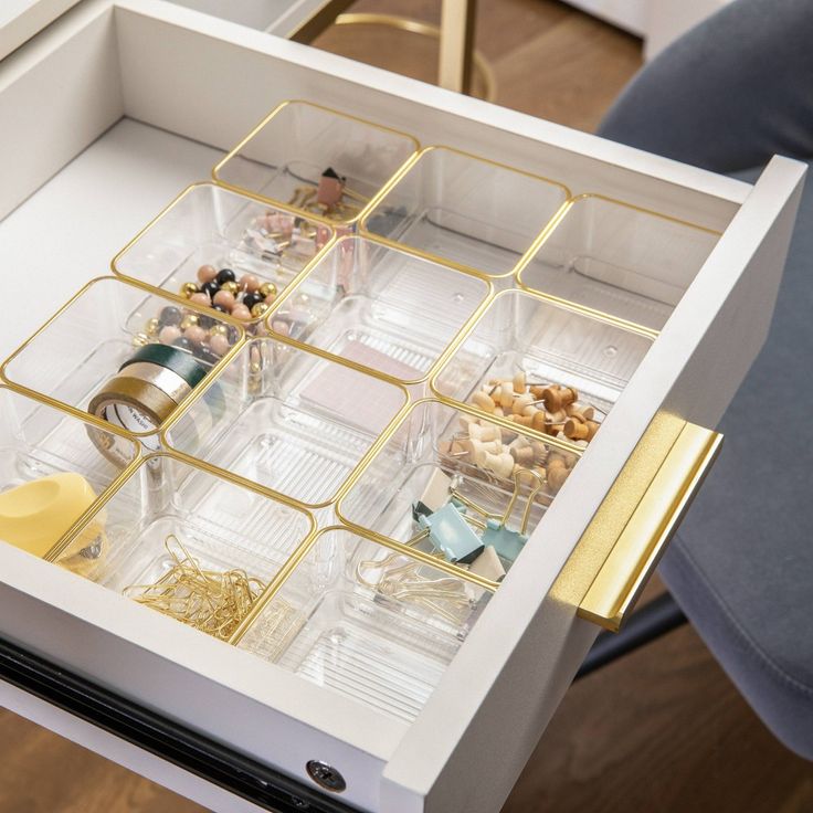 an organized drawer is shown with gold trimmings and clear containers on the drawers