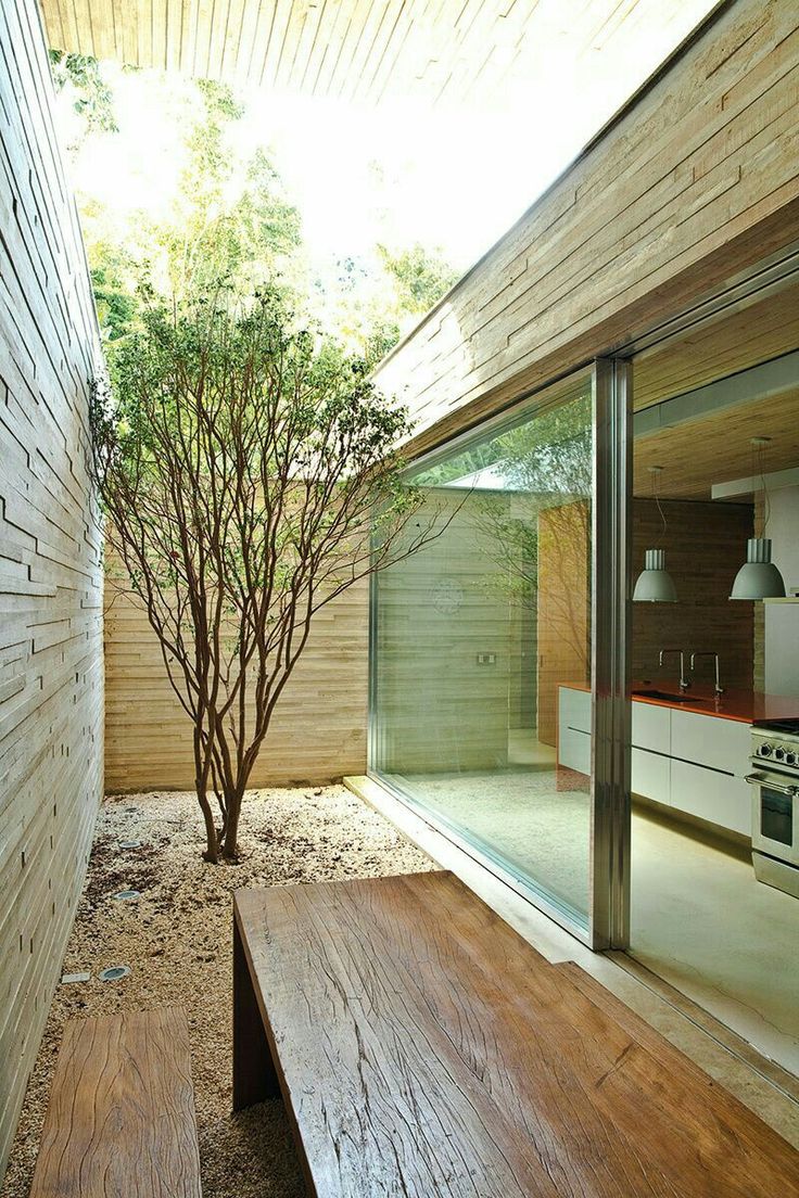 a wooden bench sitting next to a tree in front of a kitchen and living room