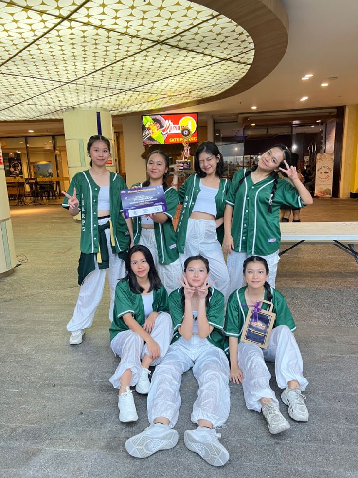 a group of young women standing next to each other in front of a building with a sign