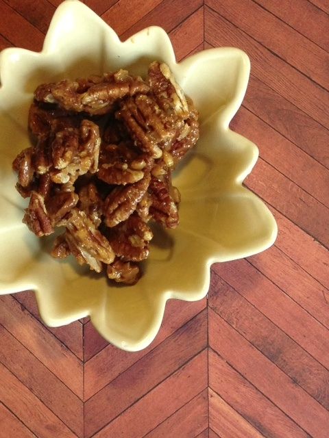 a yellow bowl filled with pecans on top of a wooden floor next to a sign that says salted caramel pecans