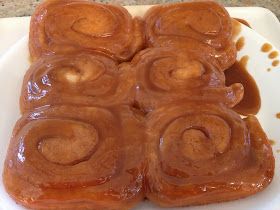 some kind of cinnamon roll on a white plate with caramel sauce in the middle