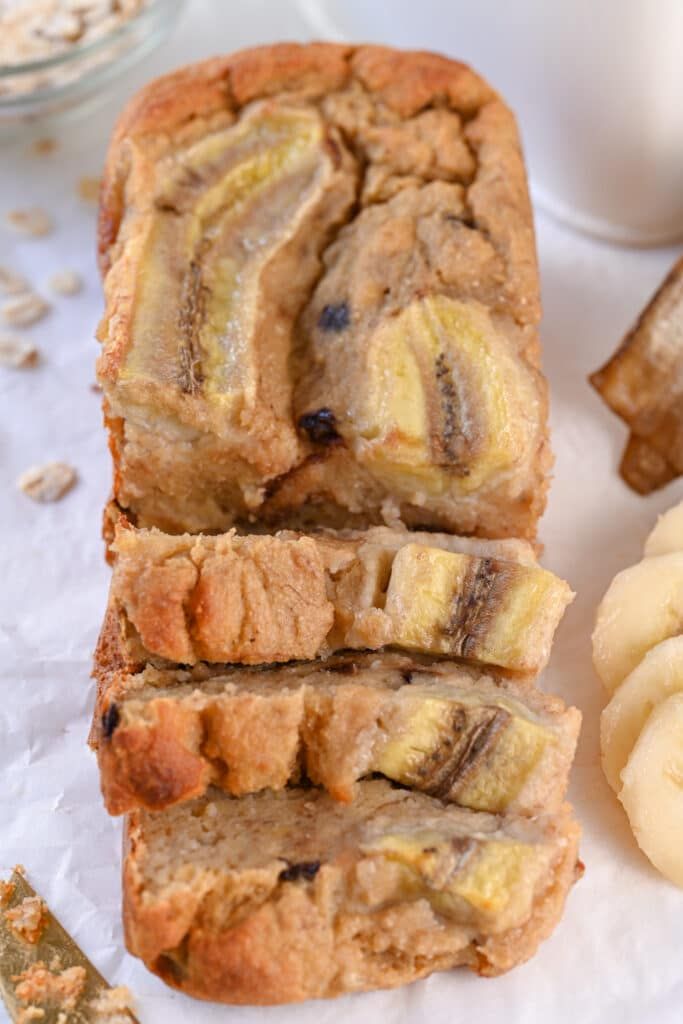 sliced banana bread sitting on top of a table next to some bananas and oats