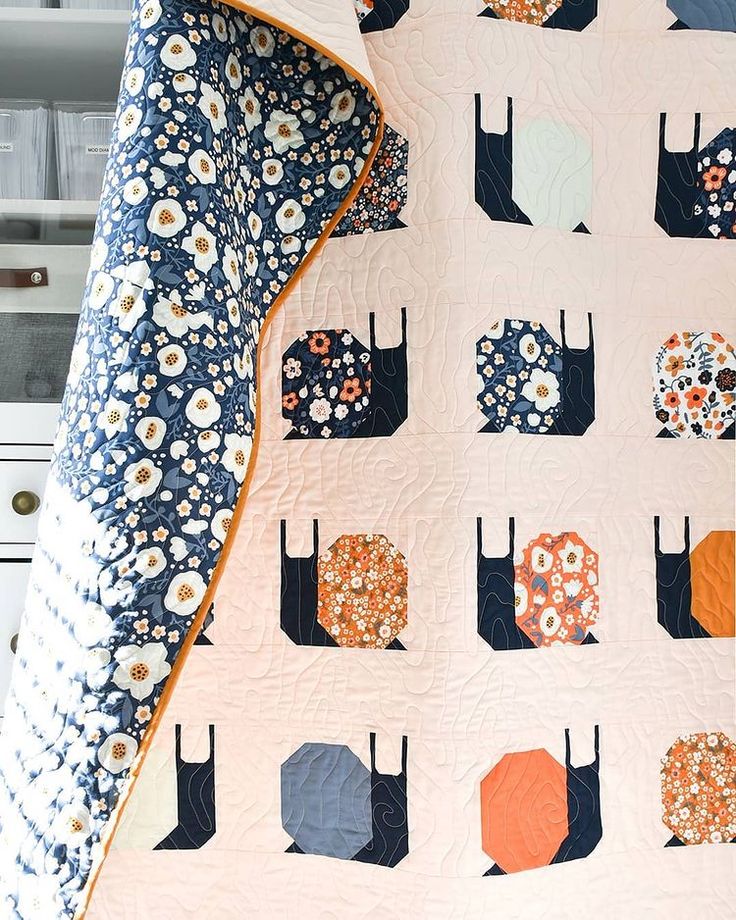 an orange and blue quilt is hanging on a white cabinet