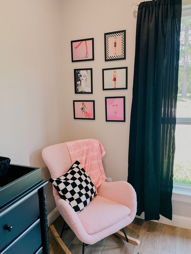 a pink rocking chair in front of a window with black and white pictures on the wall