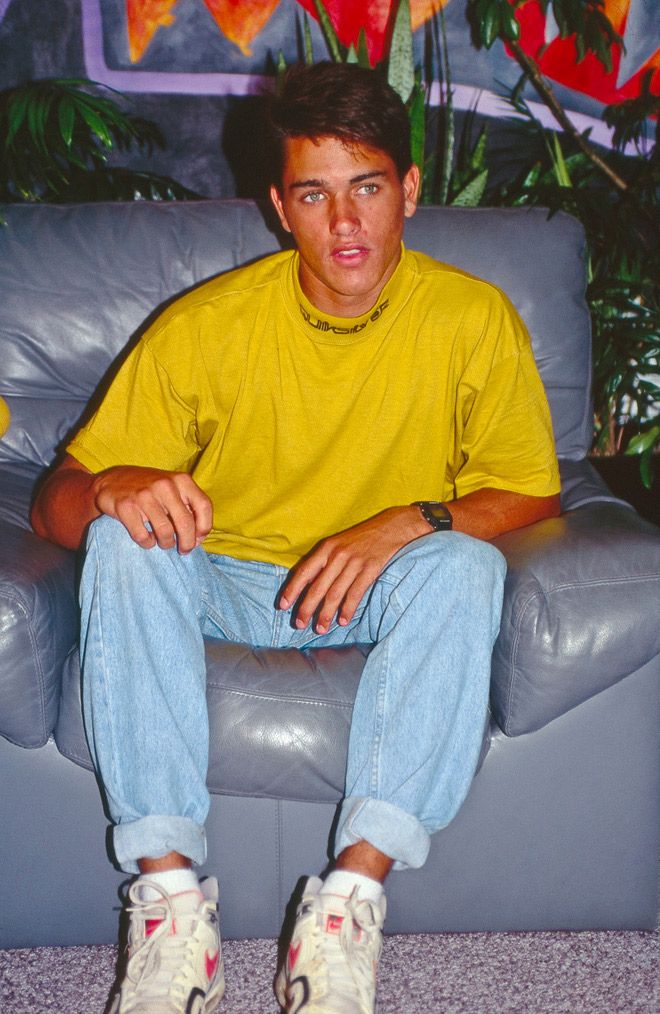 a young man sitting on top of a gray couch