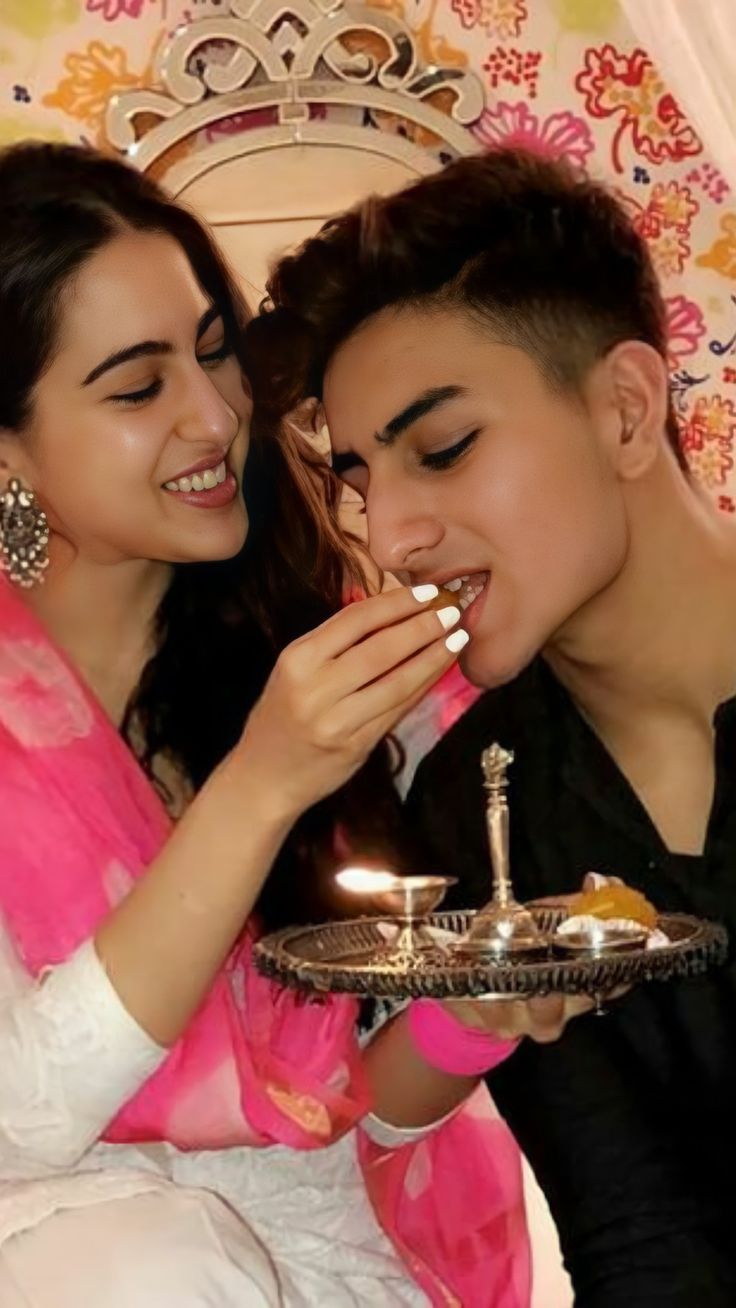 a man and woman sitting next to each other in front of a cake on a plate